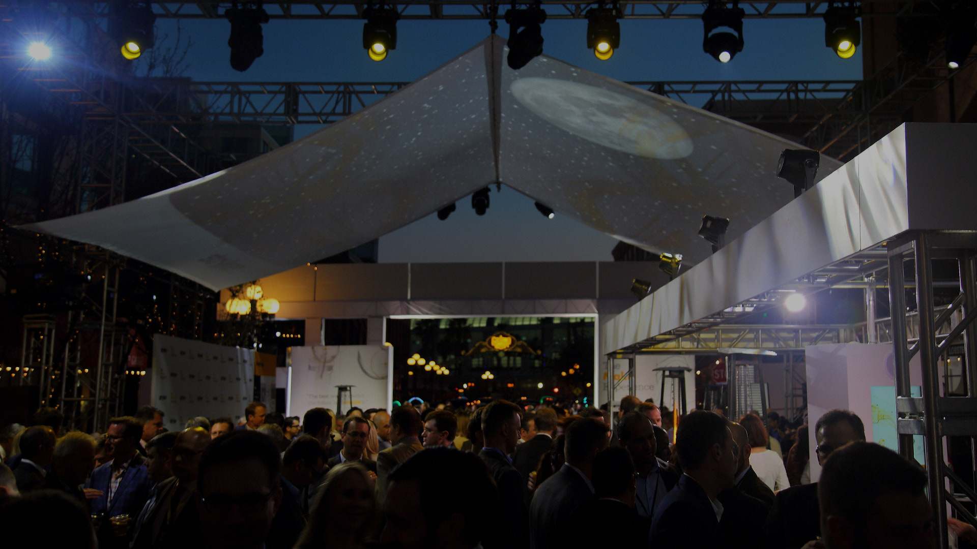 A massive crowd of professionals crowd inside of Stryker's event area at night time. Everyone looks excited. 
