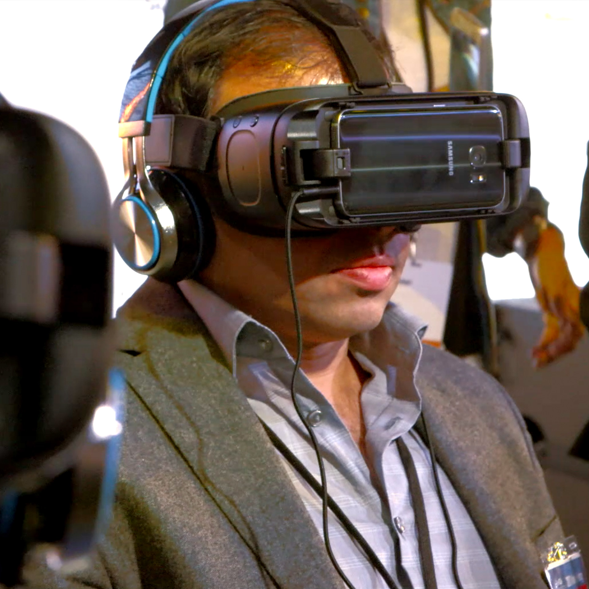 A man in a blazer wears an Oculus VR Headset. He's operating Stryker's technology in a virtual environment. 